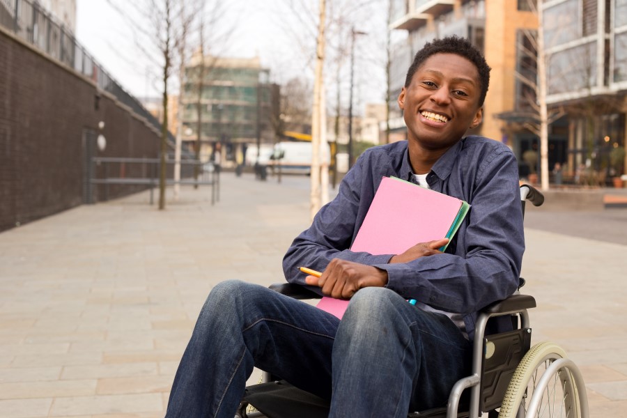 A young man sitting in a wheelchair holder school folders