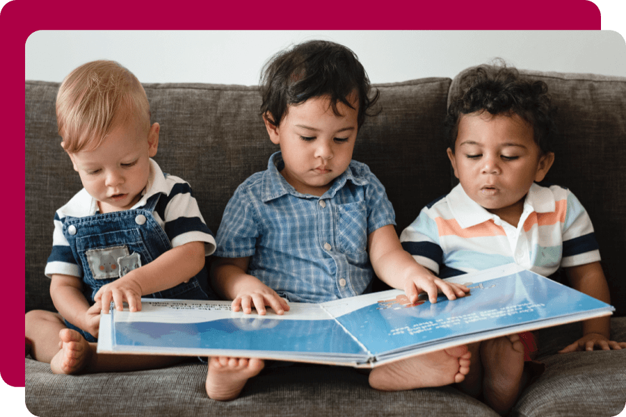 Three toddlers looking at a book